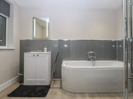 A bathroom with a bathtub, sink, and mirror at Caledfryn in Benllech