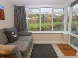 A sitting room with a sofa and large windows at Caledfryn in Benllech