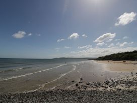 A beach with waves and people walking at Caledfryn in Benllech