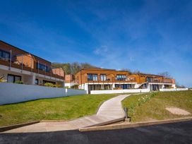 A pathway leading to modern timber and white buildings with glass balconies under a blue sky at Egret in Brixham
