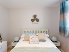 A bedroom with a bed with pillows bedside tables with lamps and blue curtains at Egret in Brixham