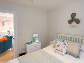 A bedroom with a bed with pillows and a bedside table next to a dresser with small vases and a mirror at Egret in Brixham
