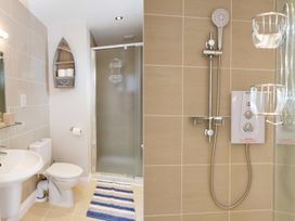 A bathroom with a pedestal sink toilet shower with frosted glass door and striped rug at Egret in Brixham