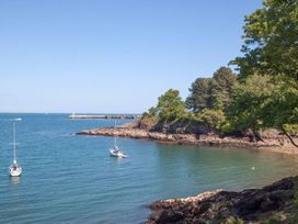 A coastal scene with two sailboats on water and rocky shore with trees at Egret in Brixham