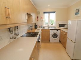 A kitchen with cabinets, sink, stove, washing machine, and refrigerator at Pheasants Walk in Falmouth