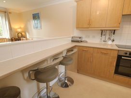 A kitchen with bar stools and wooden cabinets at Pheasants Walk in Falmouth