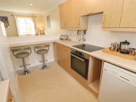 A kitchen with appliances and bar stools at Pheasants Walk in Falmouth