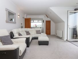 A living room with white and black leather sofas and a glass door opening to the outside at Flat 3 Channel View in Torquay