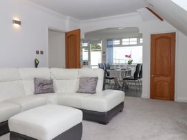 A living room with a white and black sectional sofa and a dining area with a table and black chairs at Flat 3 Channel View in Torquay