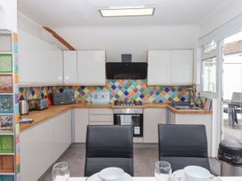 A kitchen with white cabinets multicolored tiled backsplash appliances and dining table at Flat 3 Channel View in Torquay