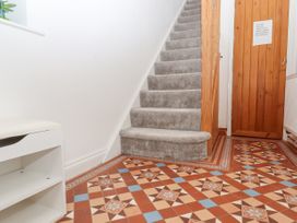 A hallway with carpeted stairs a wooden door and a patterned tiled floor at Flat 3 Channel View in Torquay