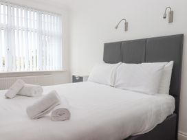 A bedroom with a double bed with white linens and rolled towels on the bed at Flat 3 Channel View in Torquay
