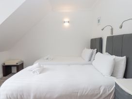 A bedroom with two single beds with white bedding and gray headboards at Flat 3 Channel View in Torquay