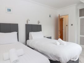A bedroom with two single beds with headboards bedside table and open door at Flat 3 Channel View in Torquay