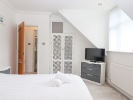 A bedroom with a bed, rolled towels, a chest of drawers with a TV, a radiator, and a doorway at Flat 3 Channel View in Torquay