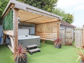 An outdoor area with a covered hot tub wooden bench artificial grass and potted plants at Flat 3 Channel View in Torquay