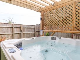 An outdoor hot tub under a wooden pergola with lattice panels and a wooden fence at Flat 3 Channel View in Torquay