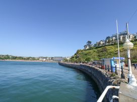 A waterfront promenade with a stone wall and railing next to water and buildings on a hill at Flat 3 Channel View in Torquay