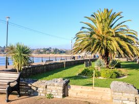 A park area with palm trees benches and a stone wall along a waterfront at Flat 3 Channel View in Torquay