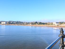 A view of a beach and calm sea with a railing in the foreground at Flat 3 Channel View in Torquay
