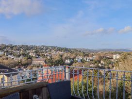 A balcony with metal railing and outdoor furniture overlooking houses and trees at Flat 3 Channel View in Torquay