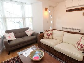 A living room with a sofa, armchair, and table at Bodefi in Nefyn