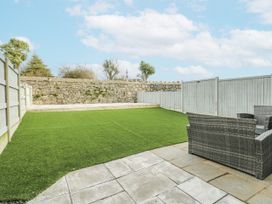 A garden with artificial grass and a stone wall at Y Ty Pren in Brynteg near Benllech