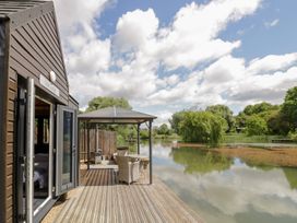 An outdoor area with a deck and chairs at Oak Lodge At Bridge Lake Farm & Fishery in Chacombe