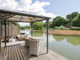 An outdoor area with a gazebo, table, and chairs by a lake at Oak Lodge At Bridge Lake Farm & Fishery Chacombe