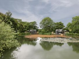 A view of houses by a pond at Oak Lodge At Bridge Lake Farm & Fishery Chacombe