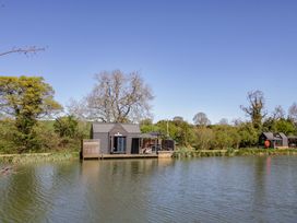 A lakeside wooden lodge with trees around at Oak Lodge At Bridge Lake Farm & Fishery Chacombe