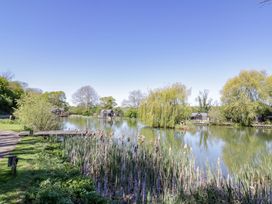 A pond with fishing huts at Oak Lodge At Bridge Lake Farm & Fishery in Chacombe