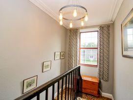 A staircase with a light fixture and framed pictures in a hallway at Beckside Farm in Bootle near Millom, Cumbria
