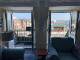 A living room with windows overlooking the harbor at Monarch in Brewers Quay Harbour