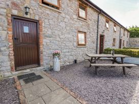 An outdoor area with a stone wall and picnic table at Bwthyn Y Wennol near Abergele
