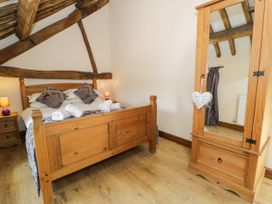 A bedroom with a wooden bed and mirror at Bwthyn Y Wennol Dolwen near Abergele