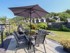 A garden with a table and chairs under an umbrella at Arthur’s Cottage in Abergynolwyn near Tywyn