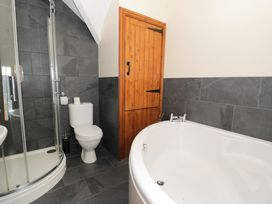 A bathroom with a shower, toilet and bathtub at Cornel Clyd in Dolwen near Abergele
