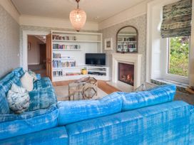 A living room with a blue sofa and bookshelf at Fern Bank in Penrith
