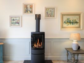 A living room with a stove and paintings on the wall at Fern Bank in Penrith