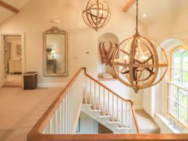 A hallway with a staircase and light fixtures at Fern Bank in Penrith