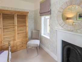 A bedroom with a wardrobe, chair, window, and mirror at Fern Bank in Penrith