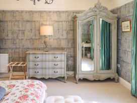 A bedroom with a lamp, wardrobe, and chest of drawers at Fern Bank in Penrith