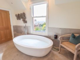 A bathroom with a bathtub and a chair at Fern Bank in Penrith