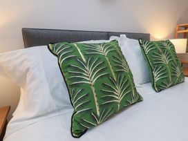 A bed with white sheets and two green palm leaf patterned pillows at Coastguards View in Whitby