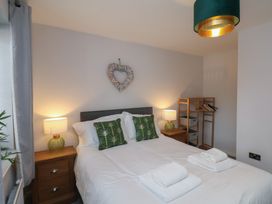 A bedroom with a double bed two bedside tables with lamps a wooden shelf unit and heart wall decor at Coastguards View in Whitby