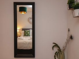 A bedroom reflected in a mirror with a bed a lamp on a nightstand and wall decorations at Coastguards View Whitby