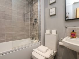 A bathroom with a bathtub shower combo toilet with towels on the seat and a sink with soap at Coastguards View in Whitby