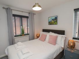 A bedroom with a double bed two pink pillows bedside tables lamps and windows with curtains at Coastguards View in Whitby