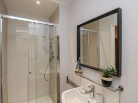 A bathroom with a glass shower enclosure a sink wall mirror and a potted plant at Coastguards View Whitby